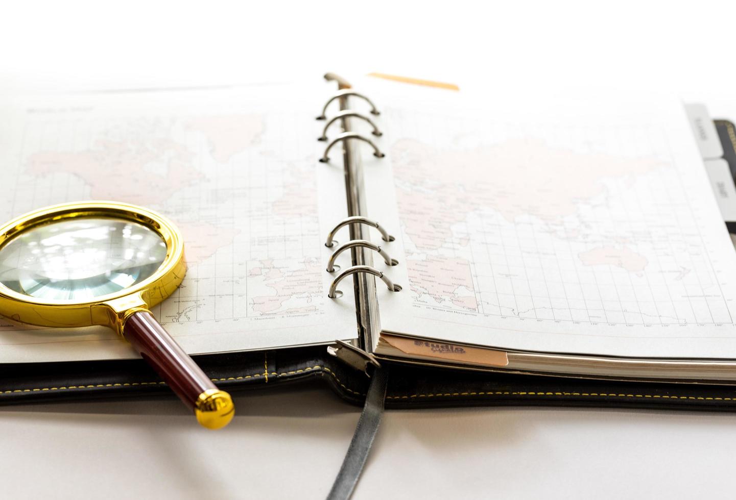 Leather ring planner with golden magnifying glass open on white workspace photo