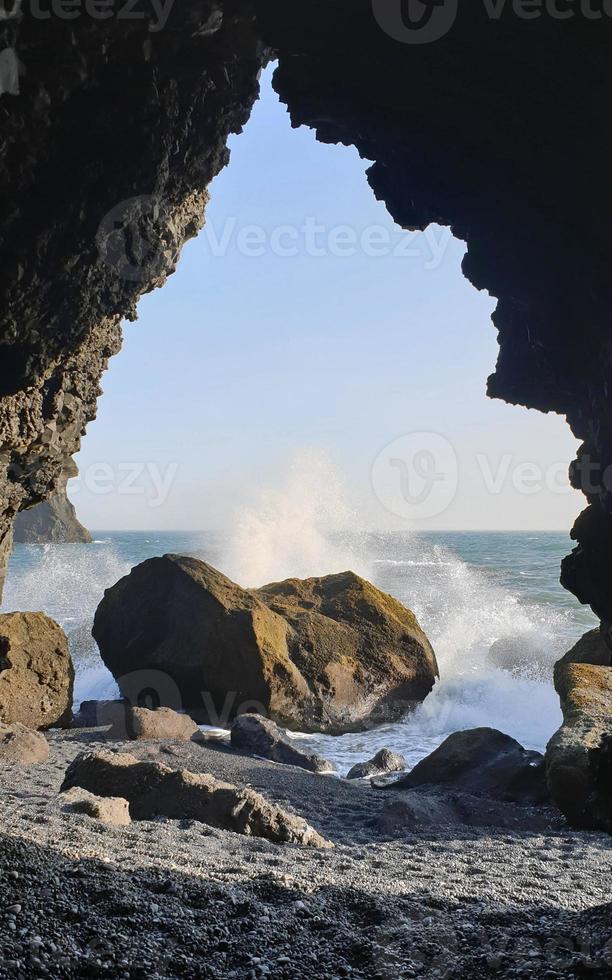 Waves coming in at Reynisfjara Black Beach, Iceland, with rock formations in the background photo