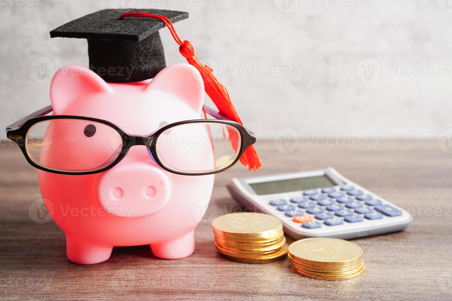 Pigging bank wearing eyeglass with coins and calculator saving bank education concept. photo