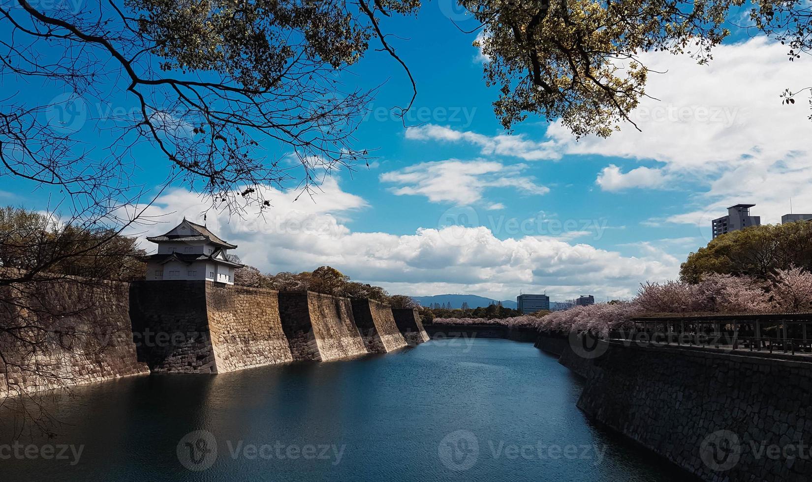 los alrededores del castillo de osaka en primavera con hermoso cielo, río tranquilo y flor de cerezo. foto