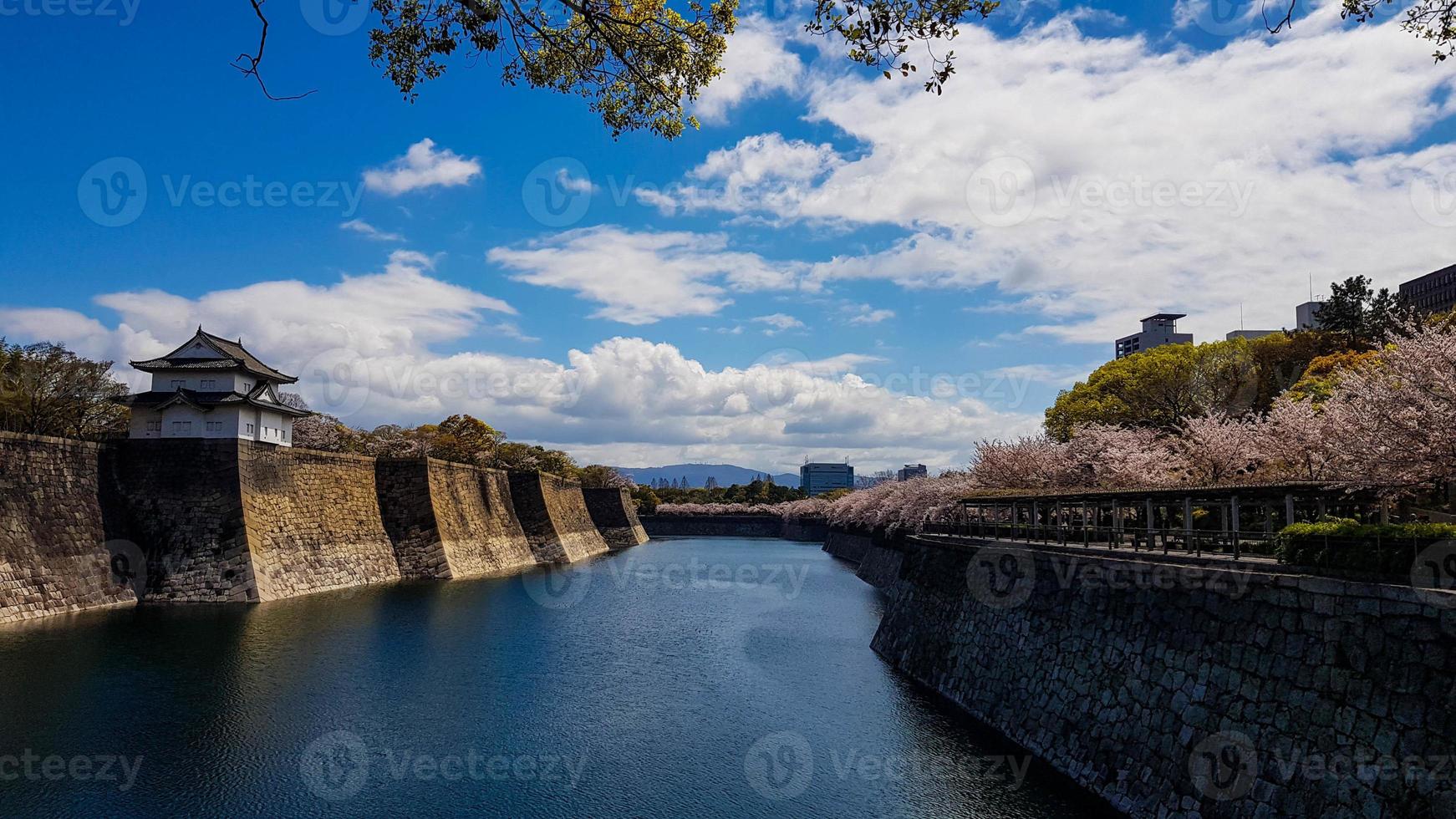 The surroundings of Osaka Castle in spring season with beautiful sky, calm river and cherry blossom. photo