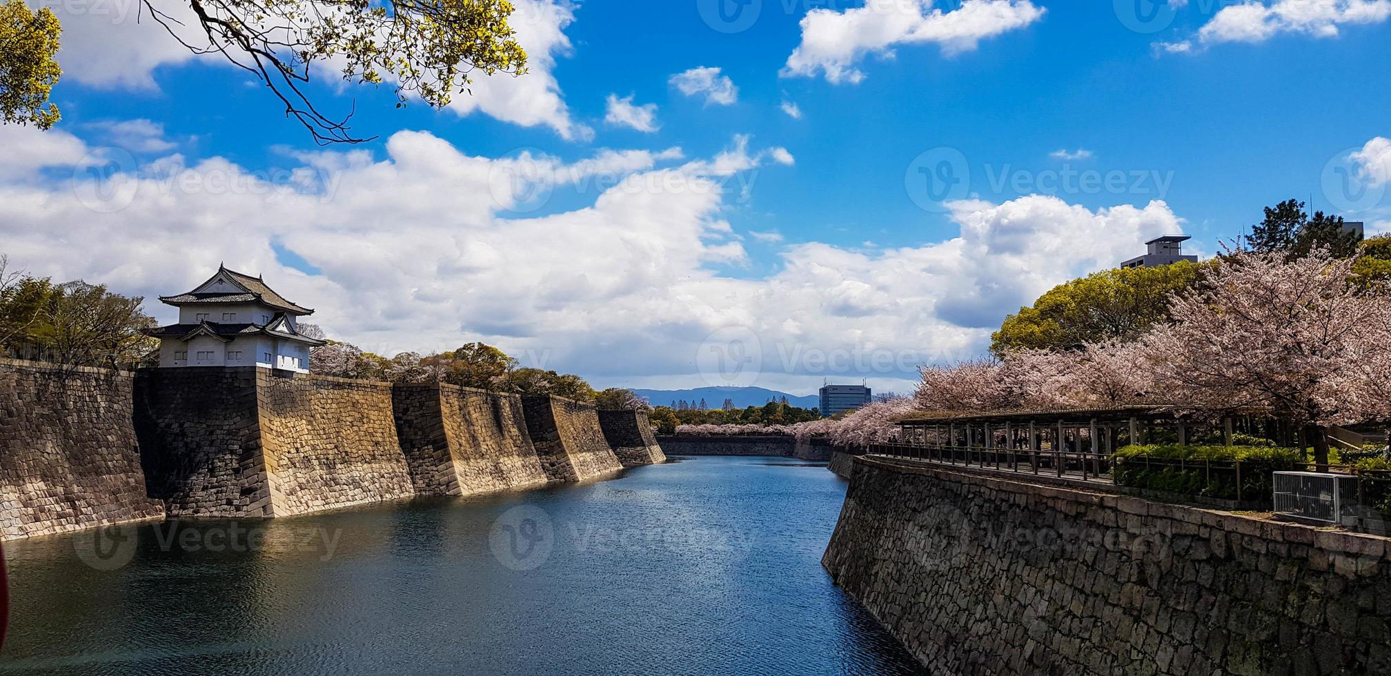 los alrededores del castillo de osaka en primavera con hermoso cielo, río tranquilo y flor de cerezo. foto