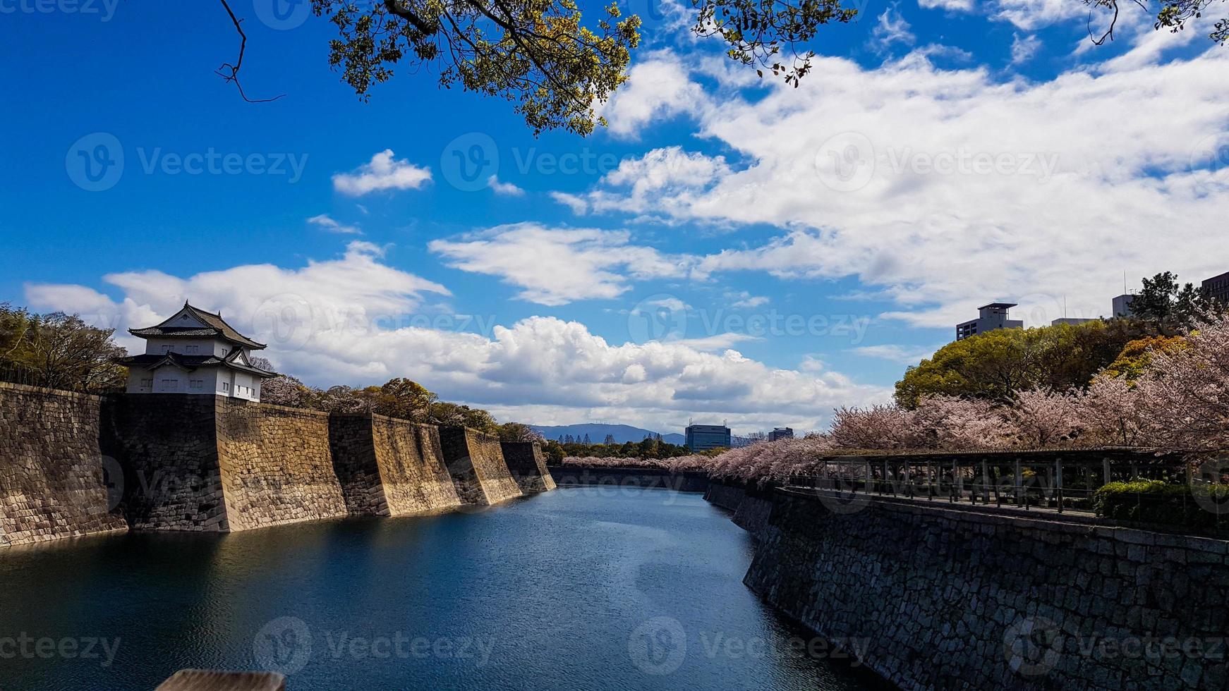 los alrededores del castillo de osaka en primavera con hermoso cielo, río tranquilo y flor de cerezo. foto