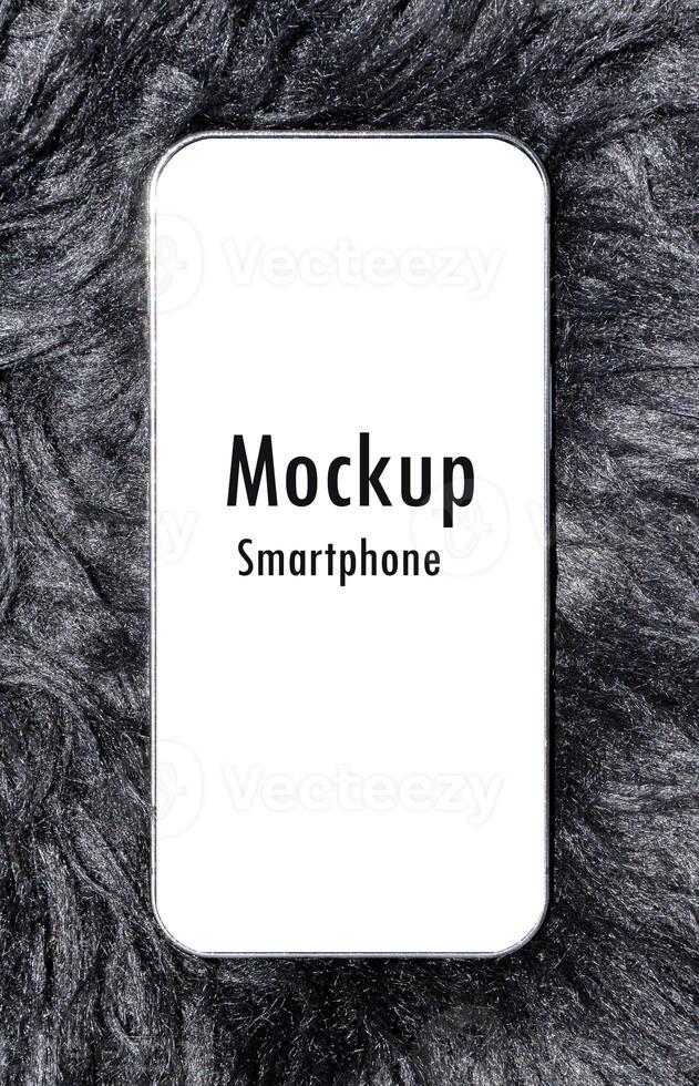 Smartphone with mockup white screen and clipping path on black wool rug photo