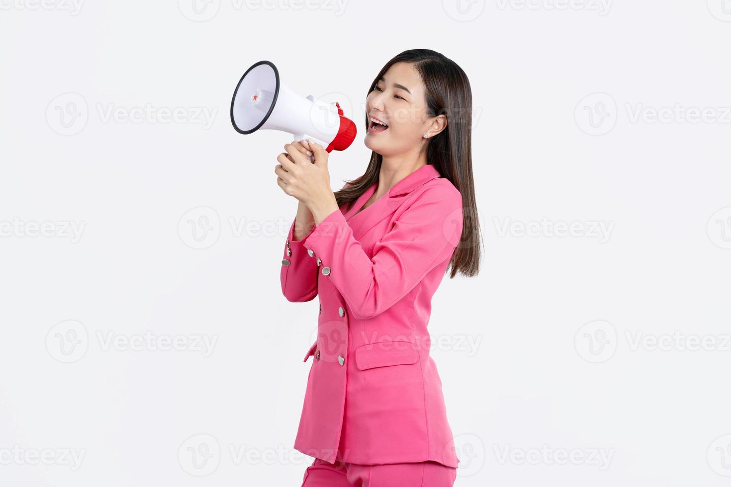 Agressive asian girl screaming towards copy space over white background, using megaphone photo