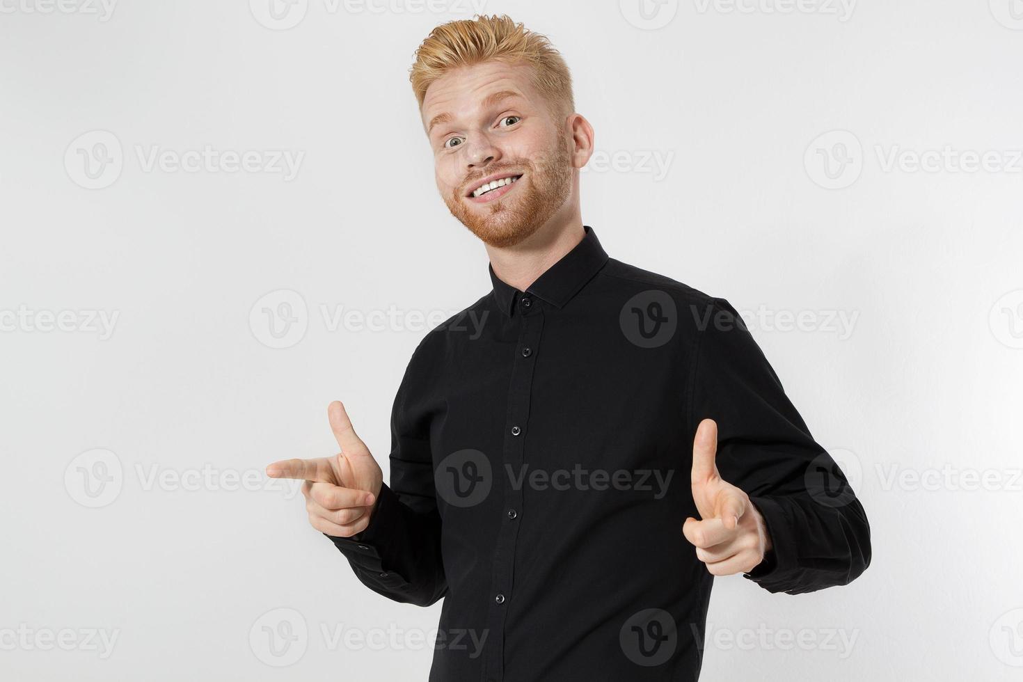 Close up of young guy with redhead and red beard isolated on white background. Stylish man in black shirt pointing copy space. Successful and happy male. Super happy and exciting person. photo