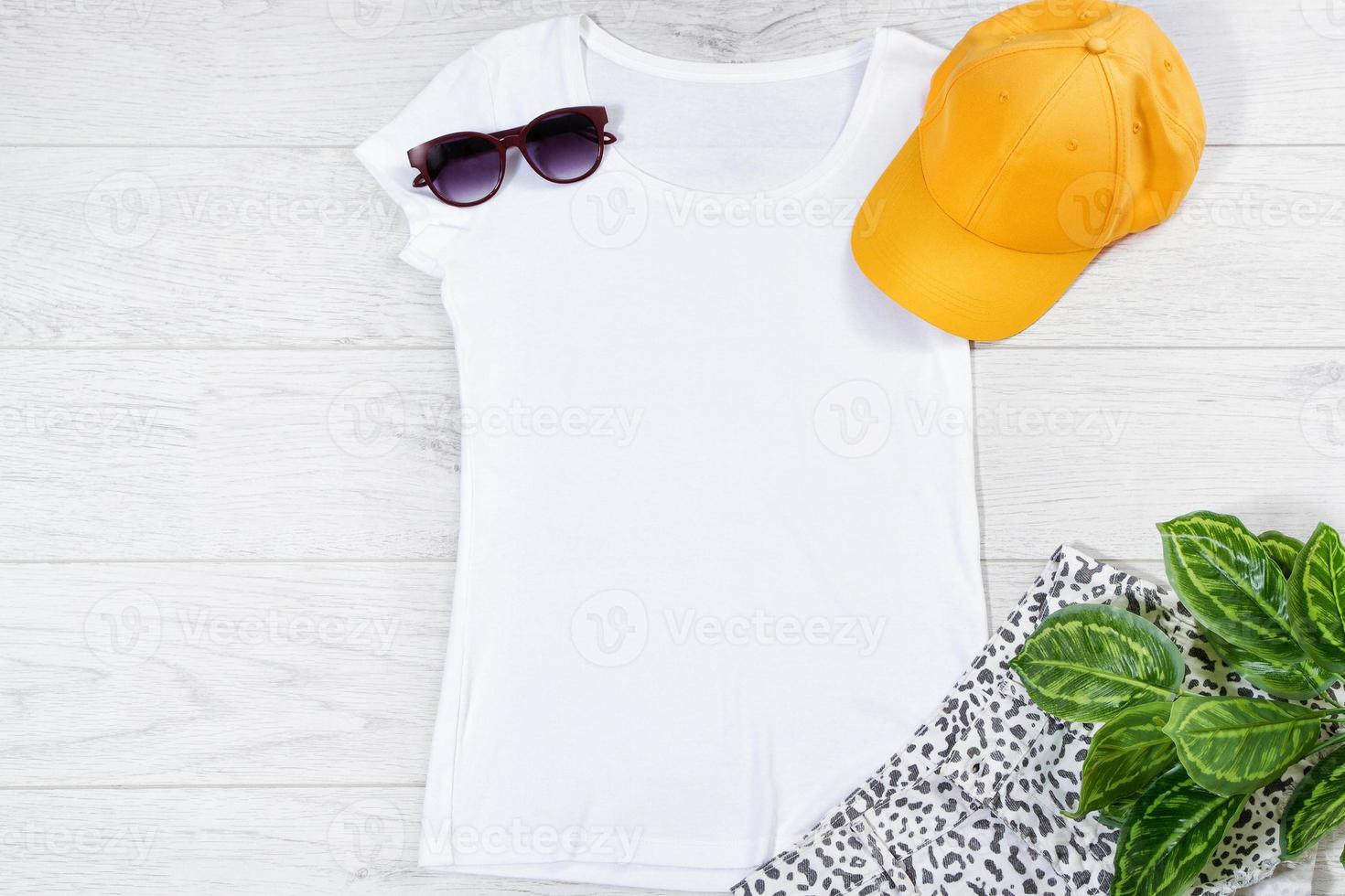 White female t shirt flip flops mock up flat lay on wooden background. Top view and copy space. Mockup t-shirt and summertime. Template blank shirt. Yellow hat photo