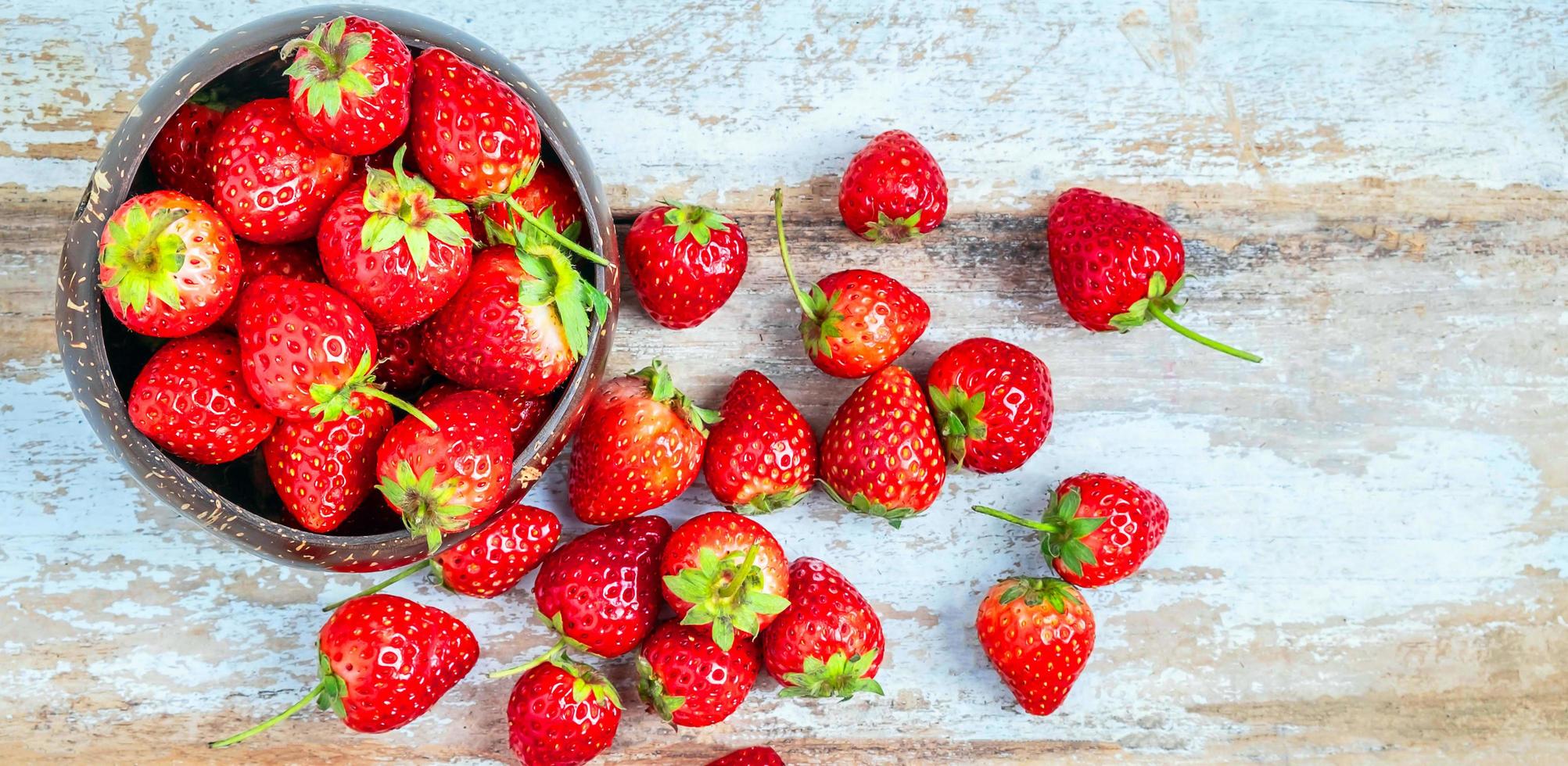 Top view of fresh red strawberries in a bowl on a blue old wooden background photo