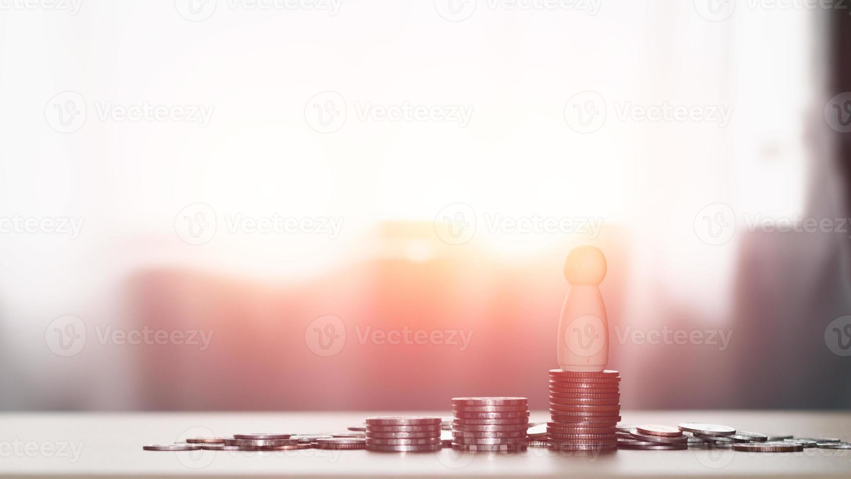 Business and financial success concept. A wooden figure stands on a coin stack. Saving and investment for the future, loans, banking, stock, and fund. photo