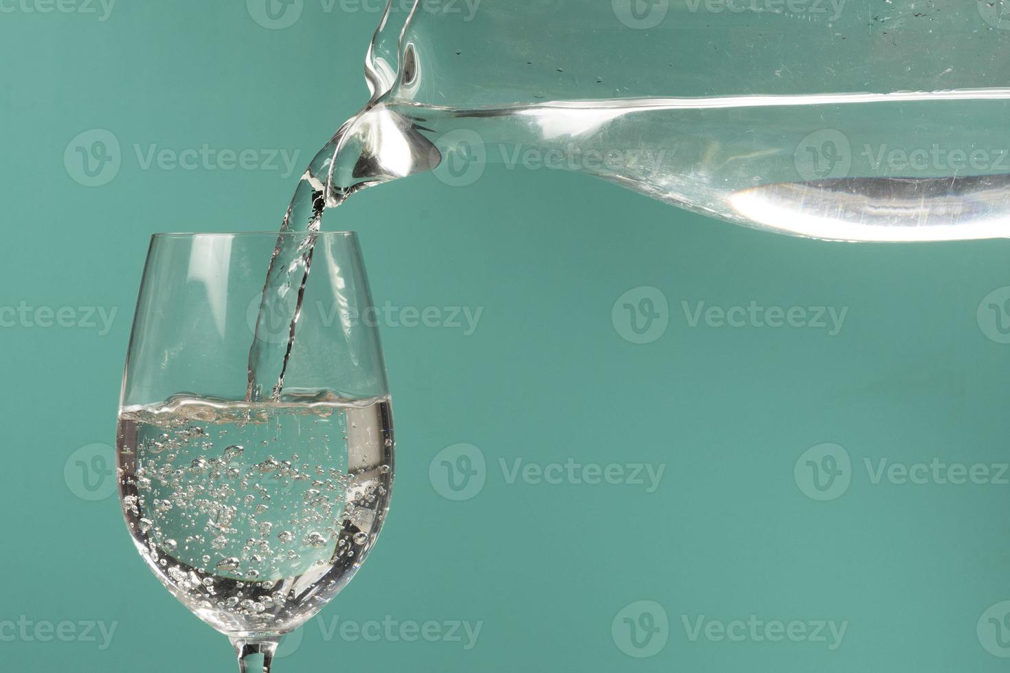 person filling a cup of water with a jar. photo