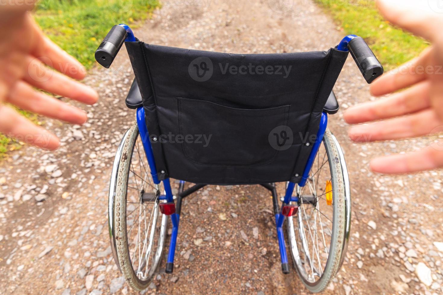 Hands holding empty wheelchair in hospital park waiting for patient services. Wheel chair for person with disability parked outdoor. Accessible for person with disability. Health care medical concept. photo