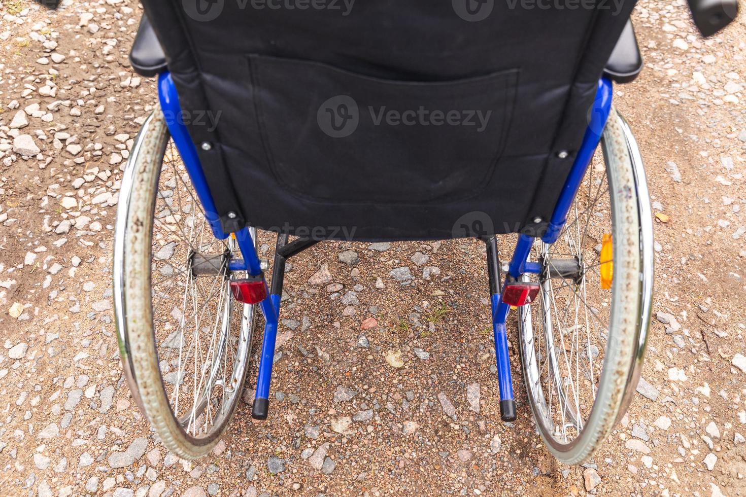 Empty wheelchair standing on road waiting for patient services. Wheel chair for people person with disability parked outdoor. Accessible for person with disability. Health care medical concept. photo