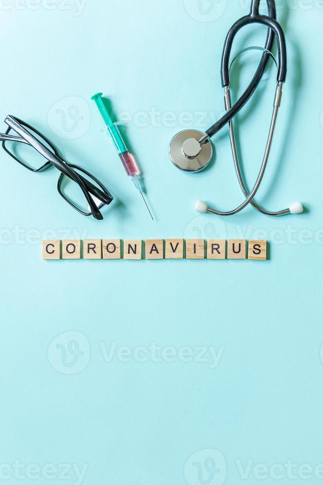 frase de texto coronavirus jeringa anteojos y estetoscopio sobre fondo azul pastel. nuevo coronavirus 2019-ncov mers-cov covid-19 concepto de vacuna contra el virus del coronavirus del síndrome respiratorio de oriente medio. foto