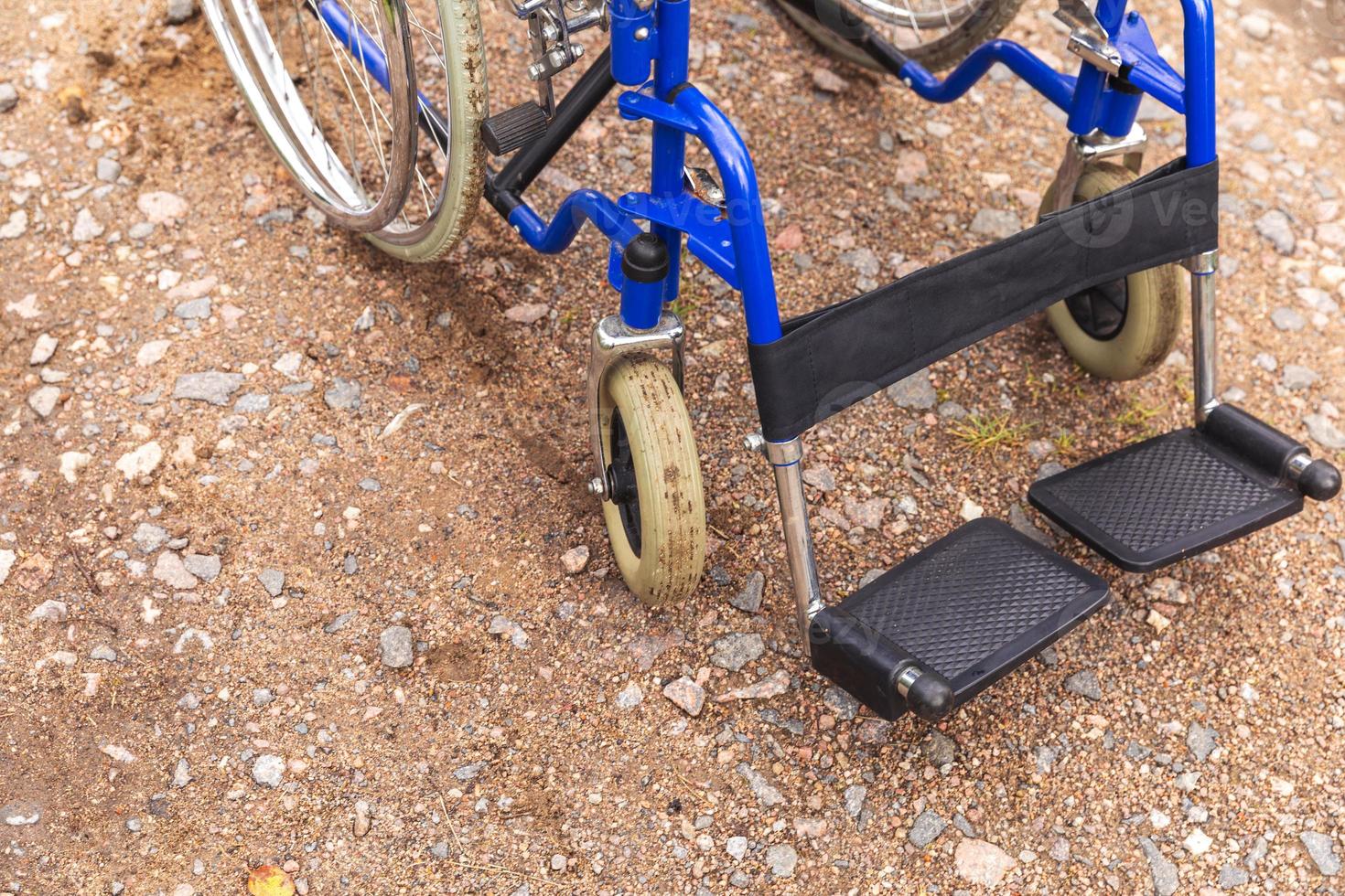 Empty wheelchair standing on road waiting for patient services. Wheel chair for people person with disability parked outdoor. Accessible for person with disability. Health care medical concept. photo