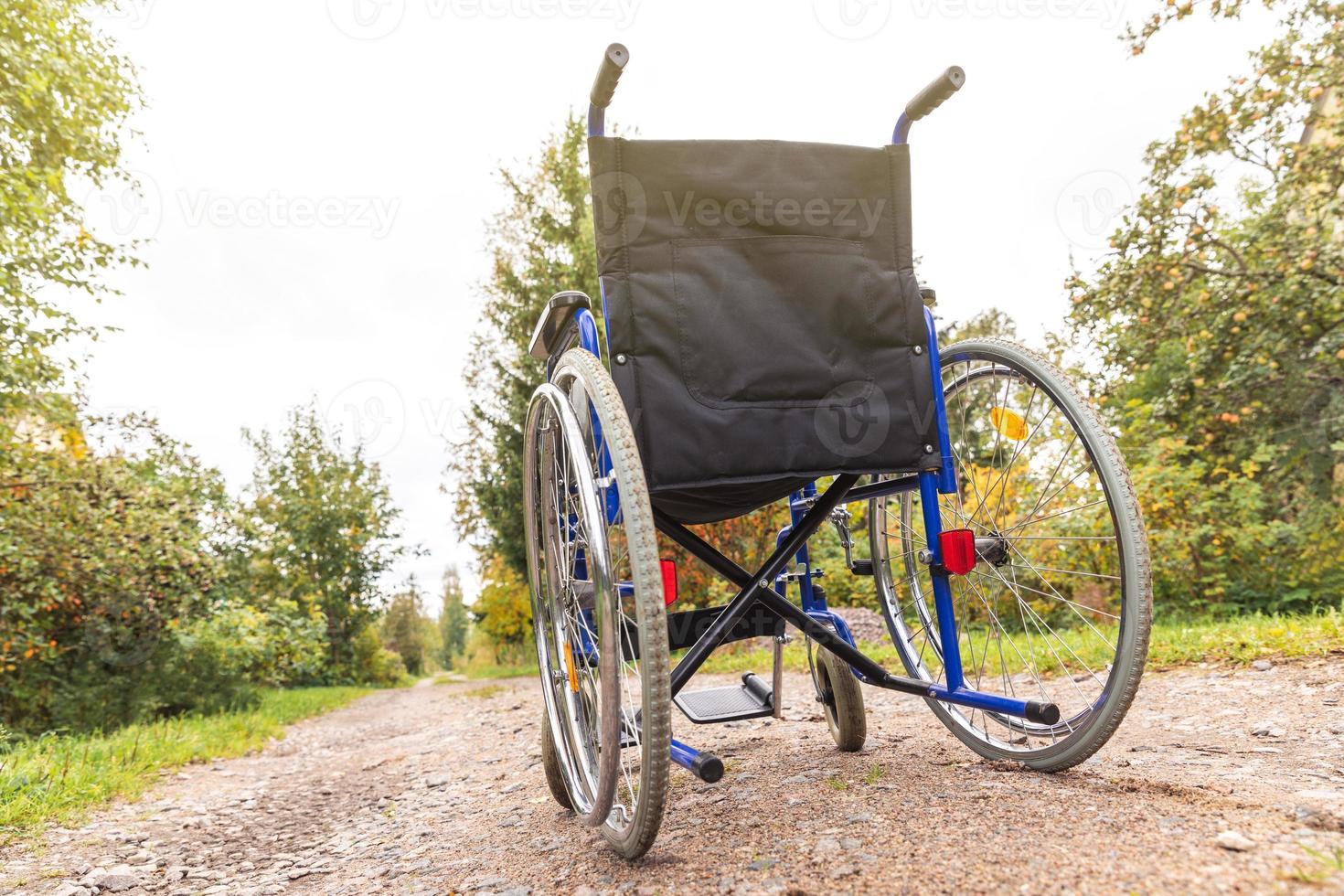 Empty wheelchair standing on road waiting for patient services. Wheel chair for people person with disability parked outdoor. Accessible for person with disability. Health care medical concept. photo