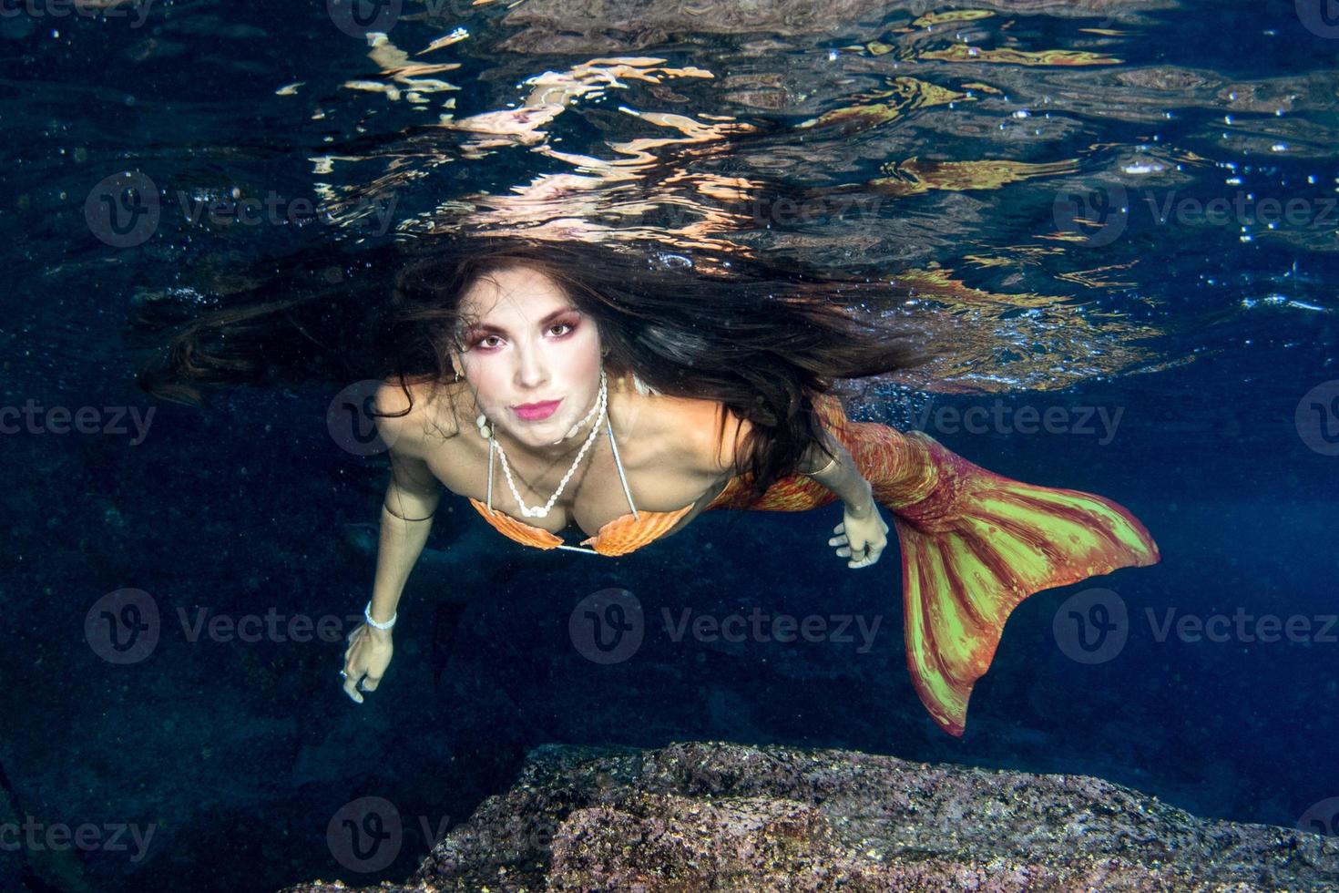 Mermaid swimming underwater in the deep blue sea photo