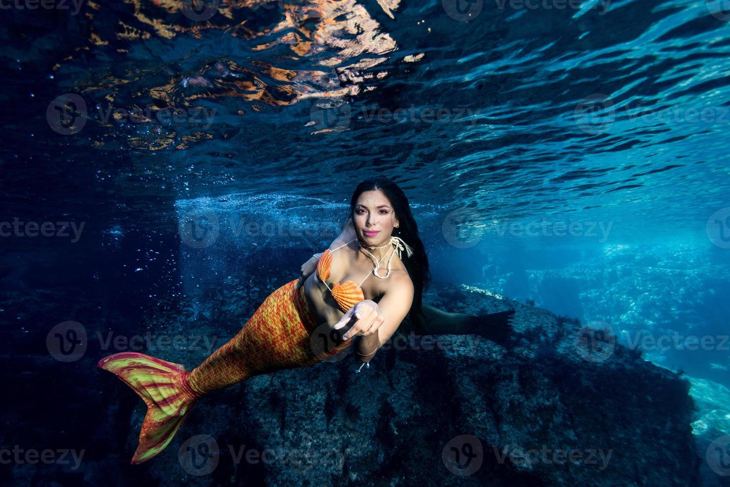 sirena nadando bajo el agua en el mar azul profundo foto