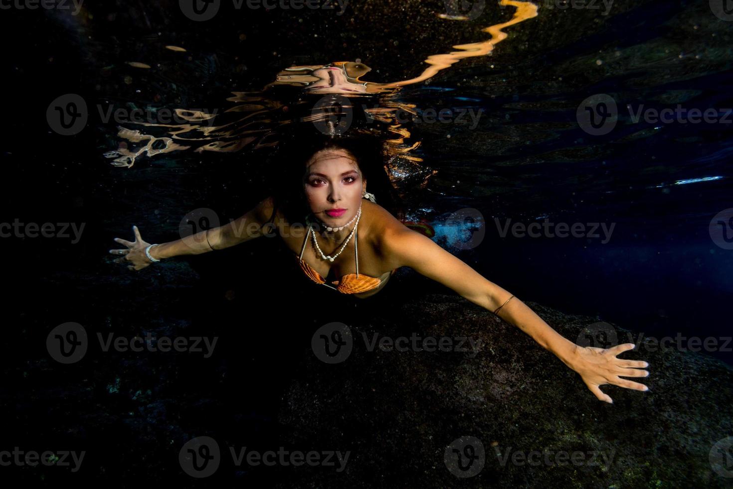 Mermaid swimming underwater in the deep blue sea photo