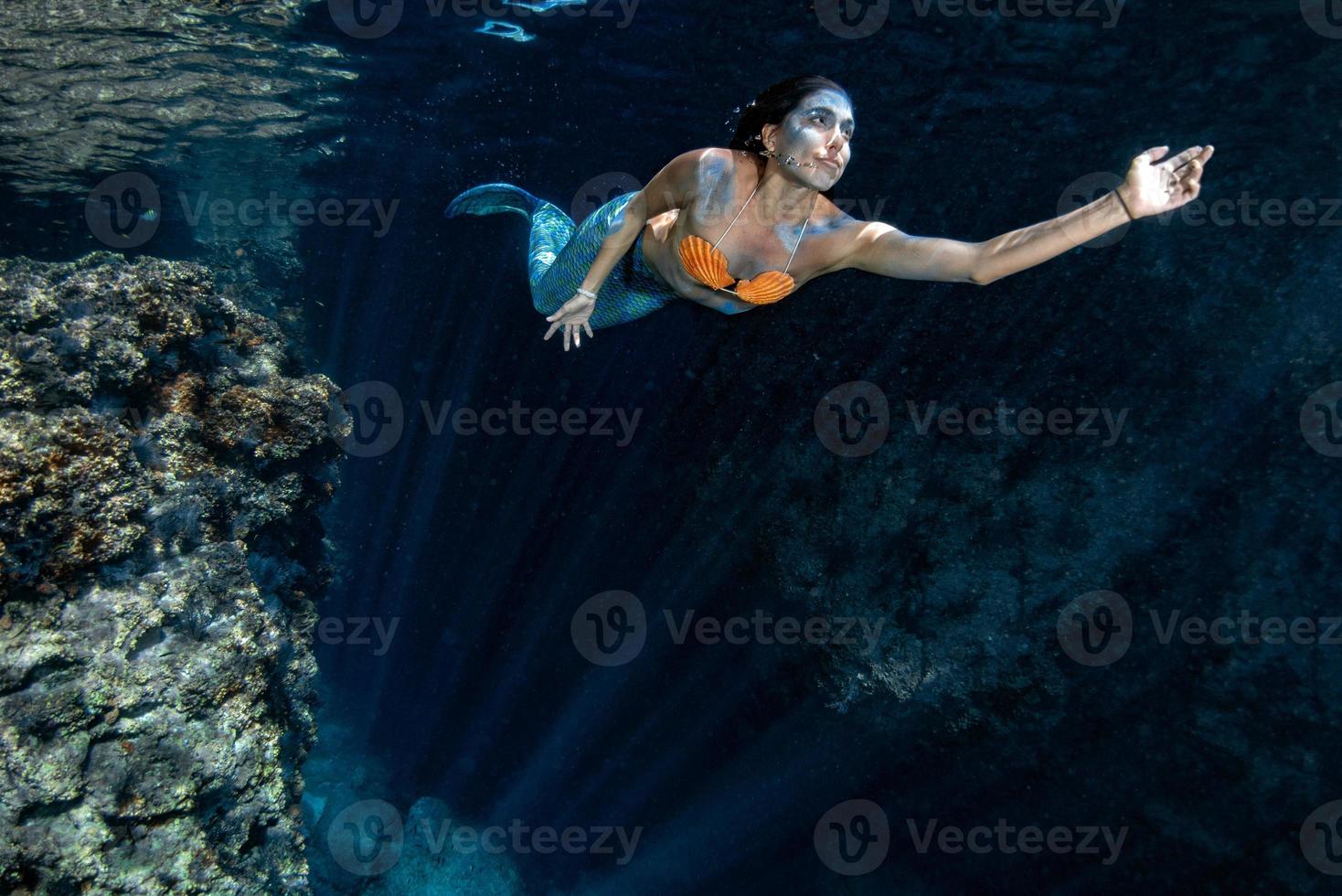 Mermaid swimming underwater in the deep blue sea photo