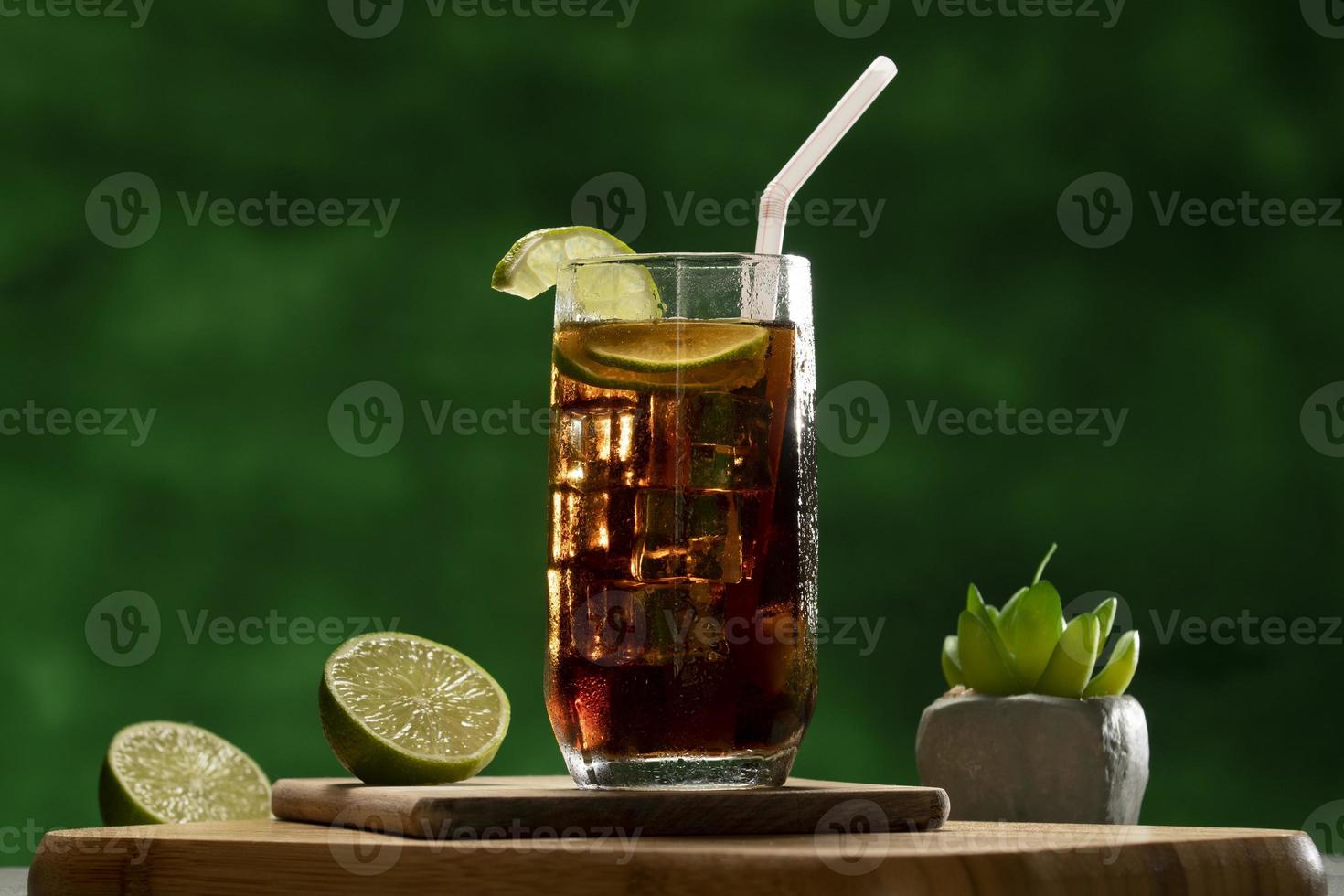 Cuba Libre drink with lime and ice on rustic wooden table photo