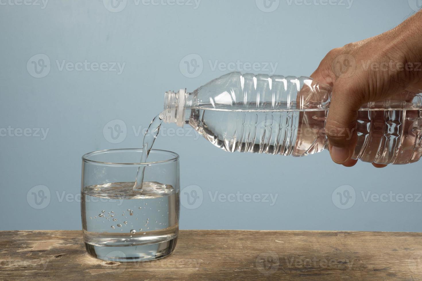 person filling a cup of water with pet bottle photo