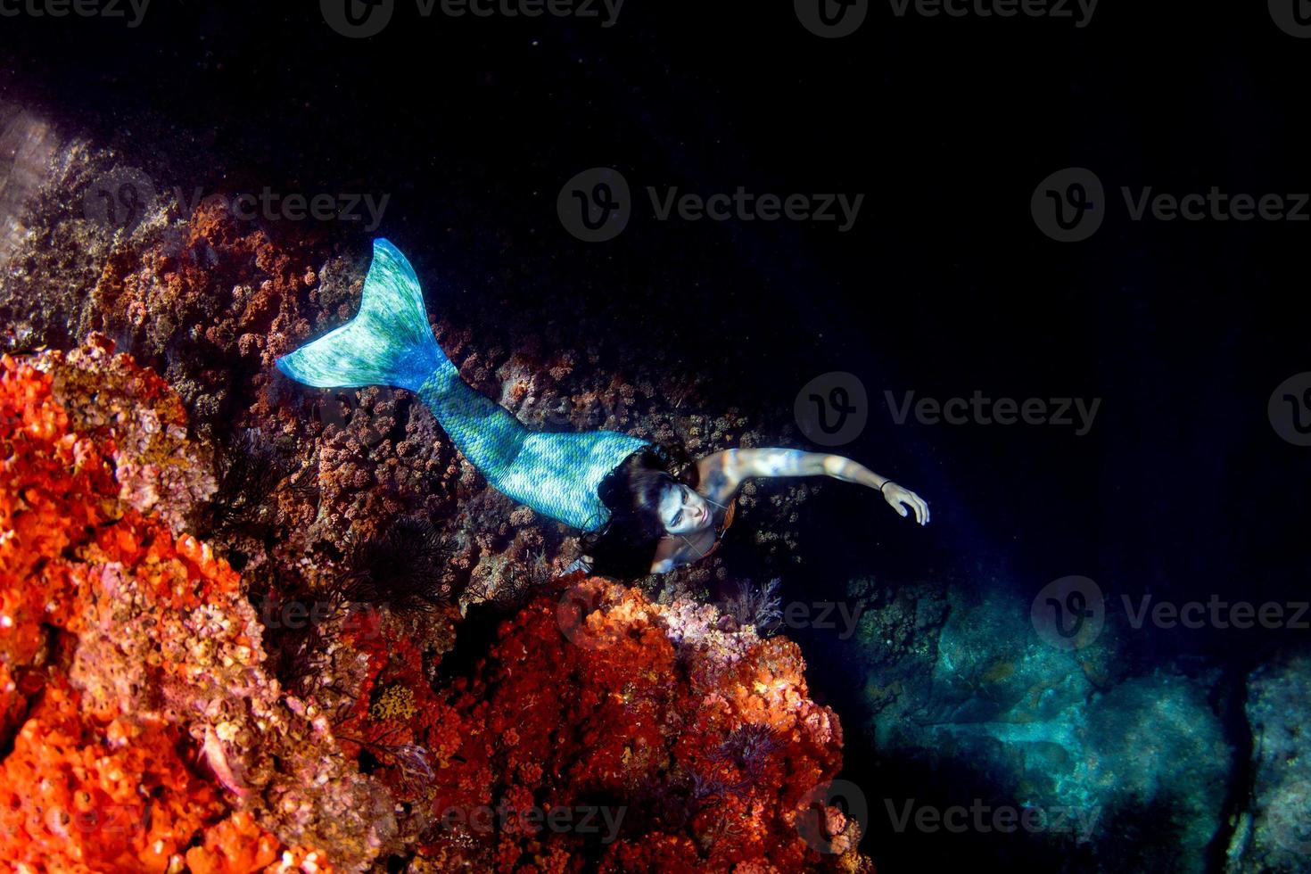 Mermaid swimming underwater in the deep blue sea photo