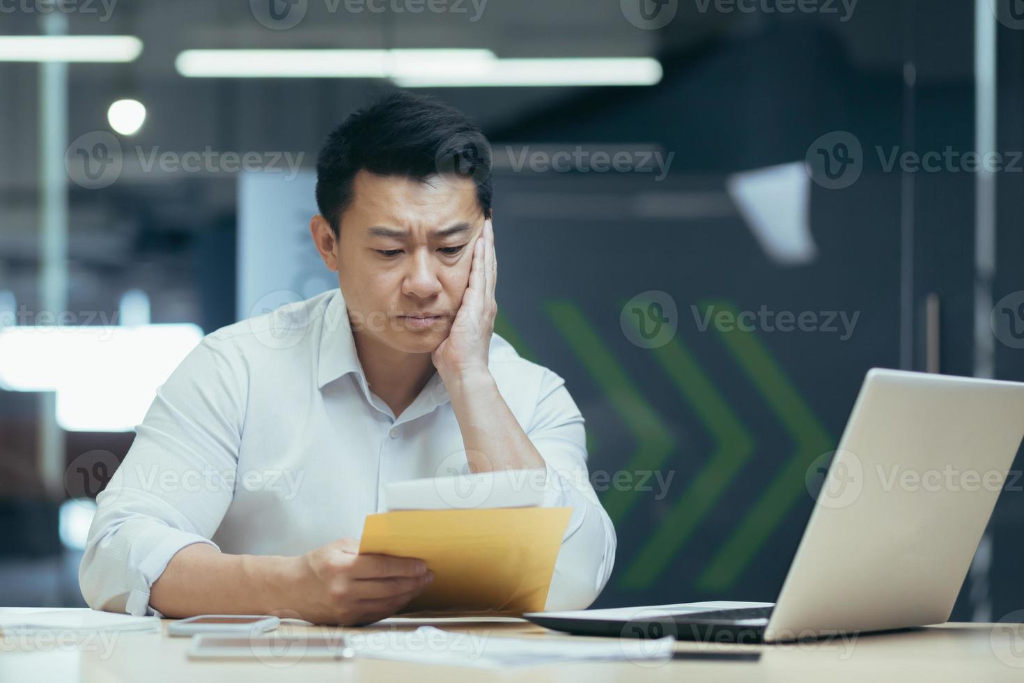 Sad over thinking asian businessman reading bad news letter from bank photo