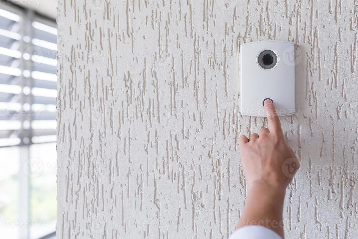 Hand of a man in a white shirt pressing the button of a door photo