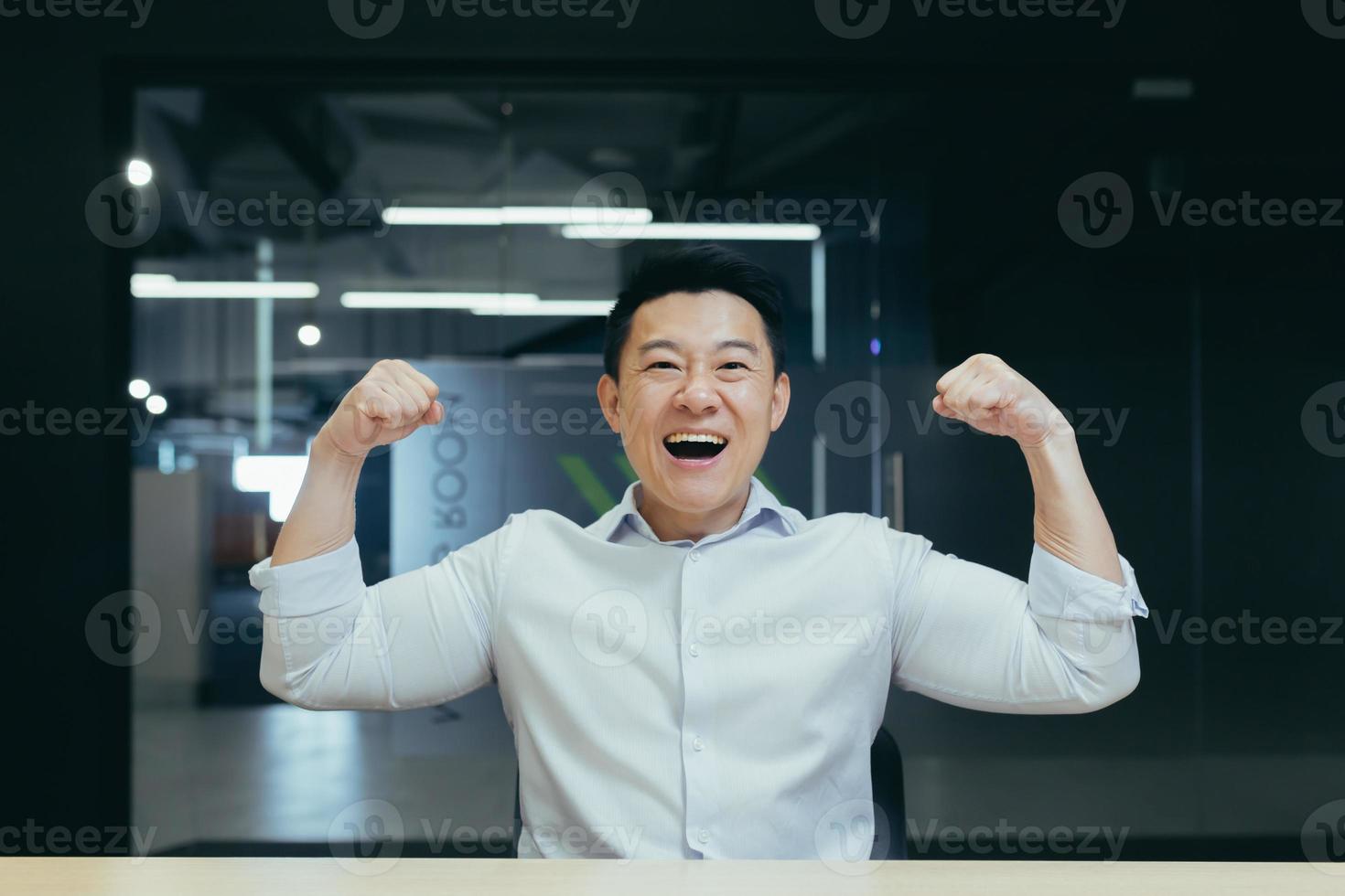 Asian super hero businessman looking at camera and smiling holding hands up gesture of strength photo