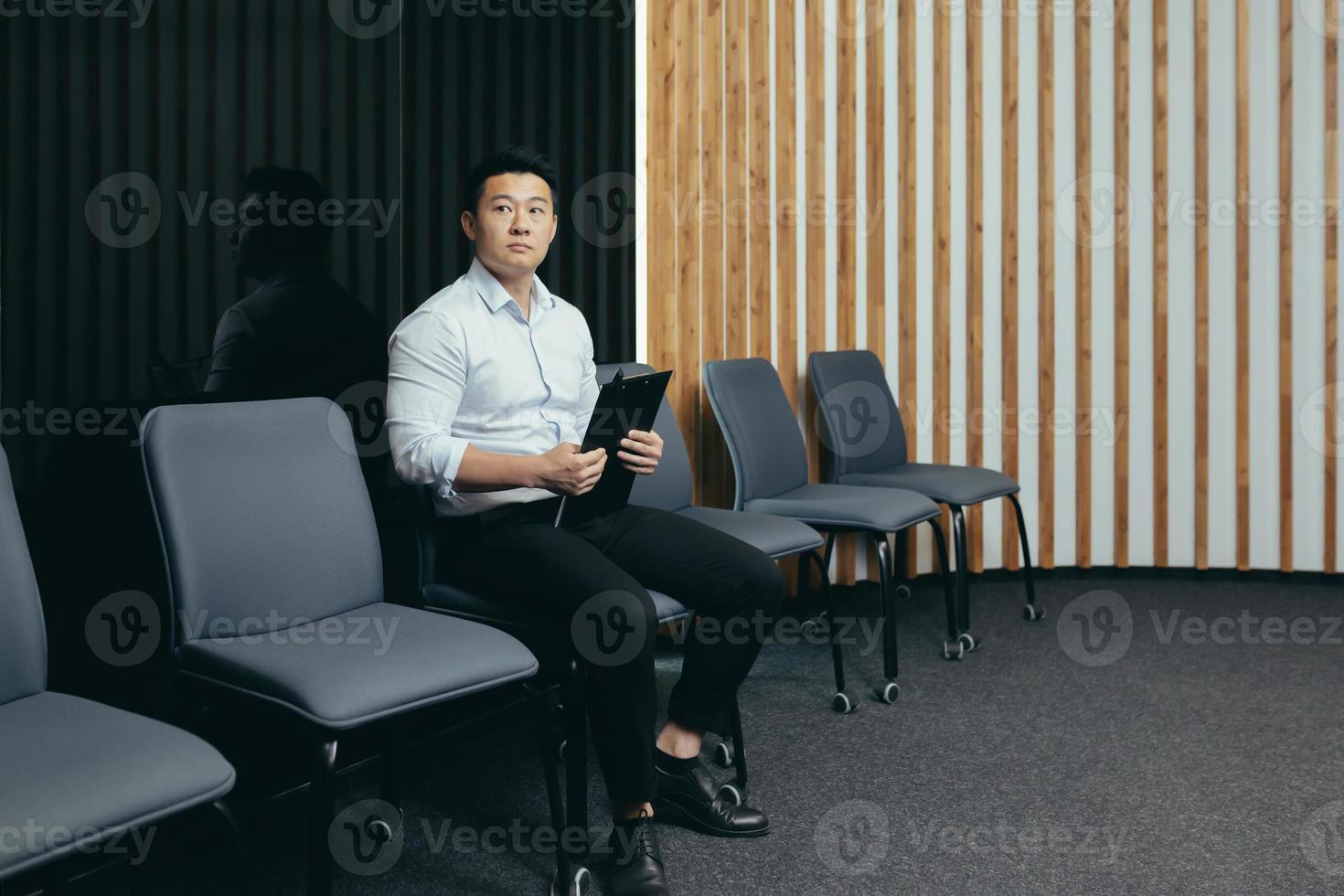 un empleado asiático está esperando en el vestíbulo, un hombre está consiguiendo un trabajo en una oficina moderna. foto