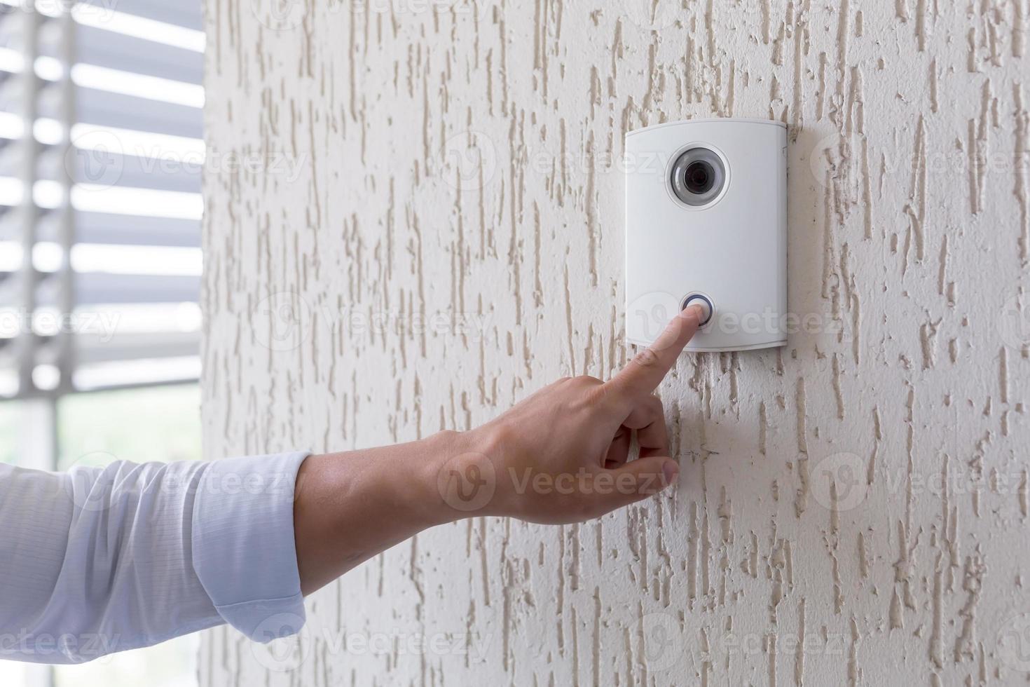 Hand of a man in a white shirt pressing the button of a door photo