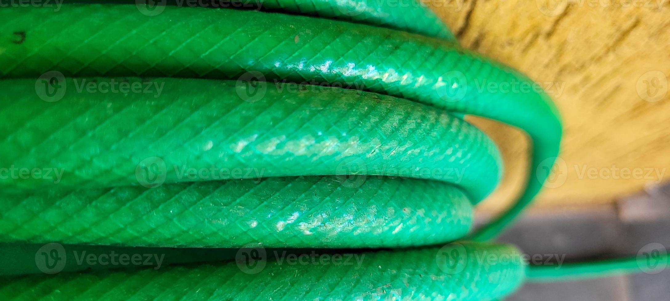 green garden hose rolled up in yard on a sunny day photo