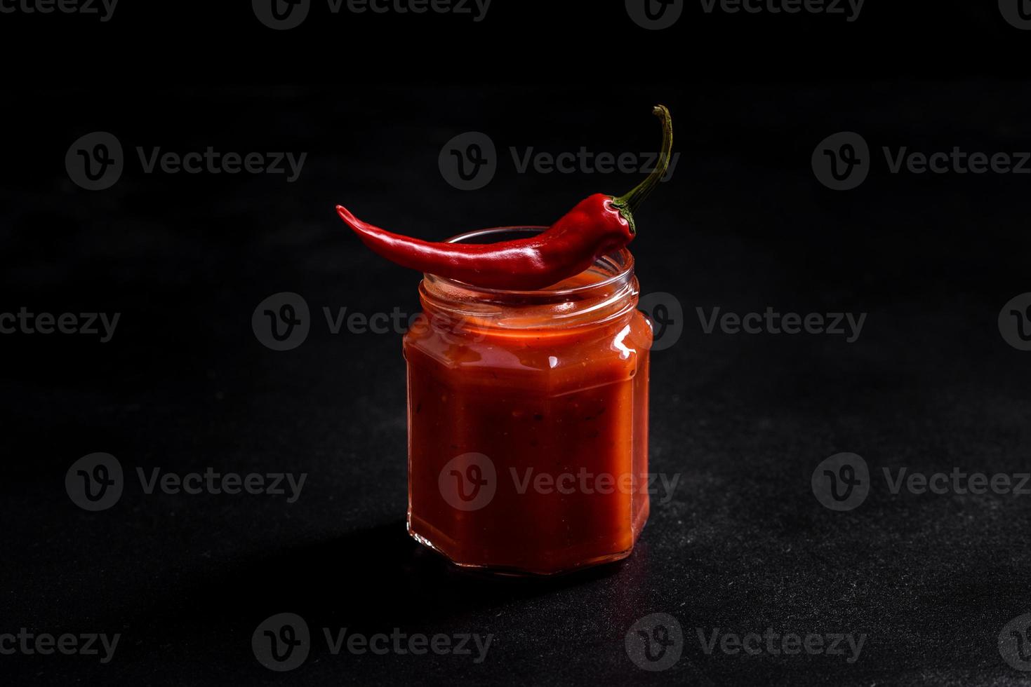 Glass jar with homemade classic spicy tomato pasta or pizza sauce with spices and herbs photo