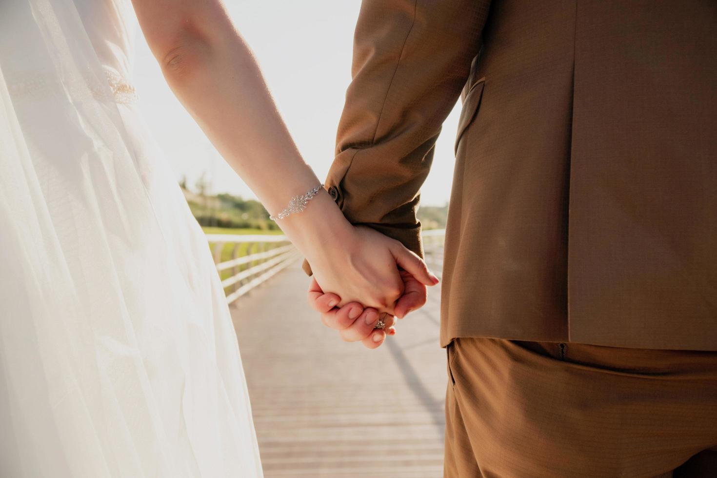 Cerca de lindos jóvenes recién casados sosteniendo sus manos contra el mar en calma con el faro foto