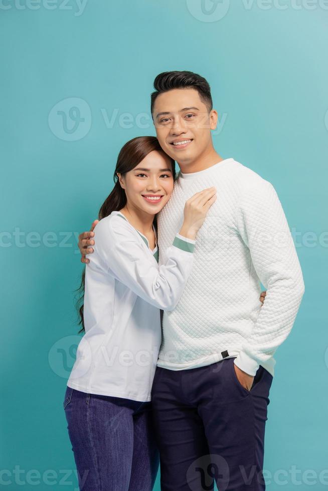 Studio shot of romantic couple posing with smile. Front view of girl and boy hugs on blue background. photo