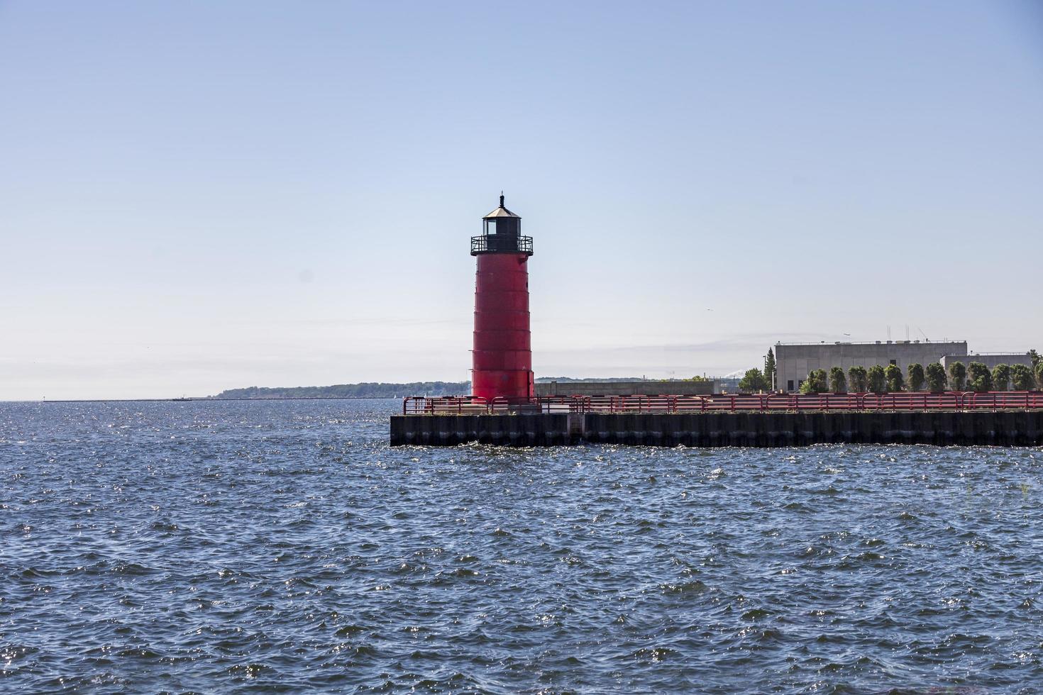 Red and black lighthouse on a jetty on a lake photo