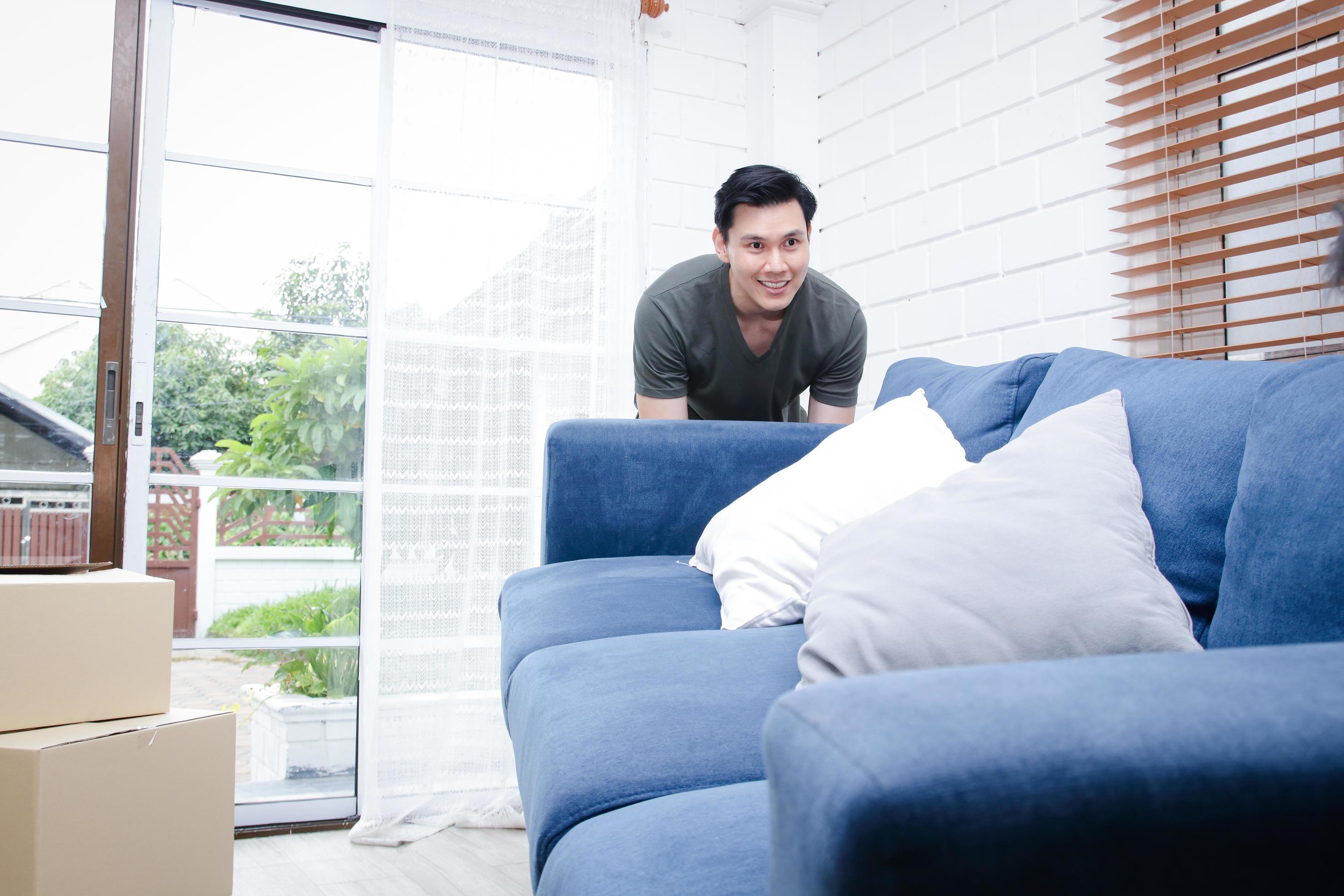An Asian man moves into a new home. Help each other move the sofa to