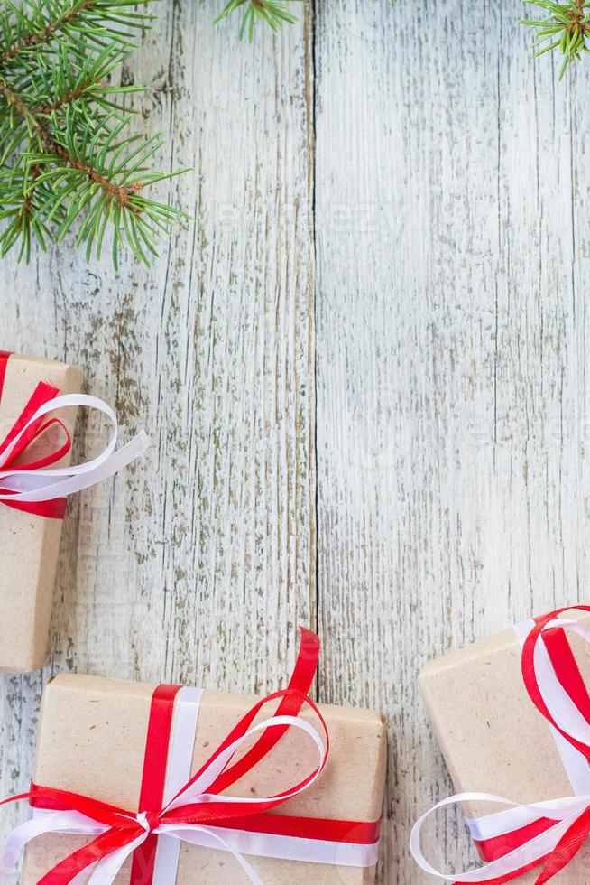 Border of Christmas gift boxes and fir tree branch on wooden table. photo