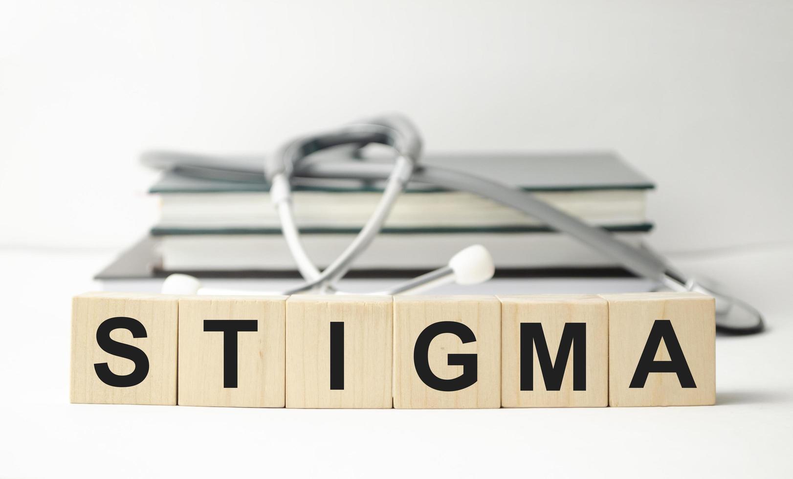 STIGMA word, text, written on wooden cubes, building blocks, over white background with reflection. photo