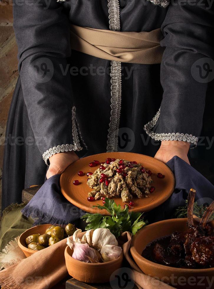 A vertical shot of a waitress presenting a kuchmachi and tomahawk steak in the background photo