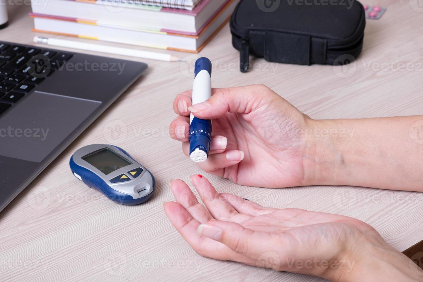 Female hands with a glucometer at the desk. The lifestyle of a person with diabetes, measuring the level of glucose in the blood photo