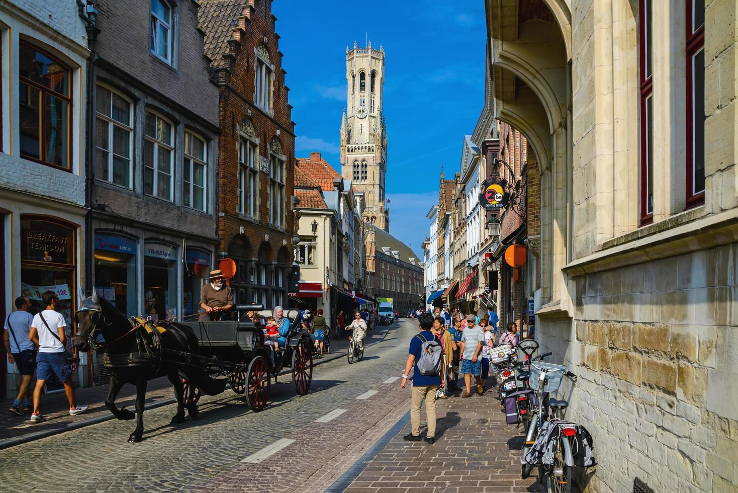 BRUGES, BELGIUM - September 19, 2014. Old narrow street on the city historic center, view to the Belfry tower on the end and lots of tourists. photo