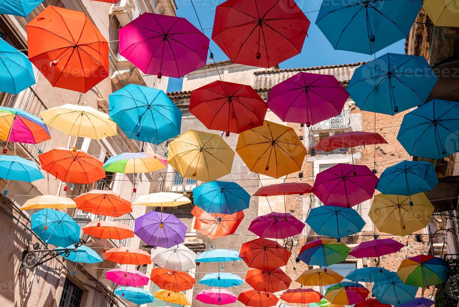 View of beautiful multicolored umbrellas hanging amidst buildings during summer photo