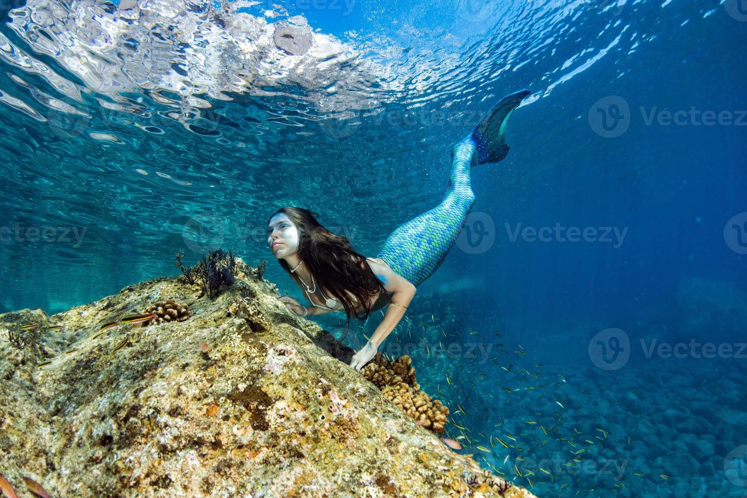 Mermaid swimming underwater in the deep blue sea photo