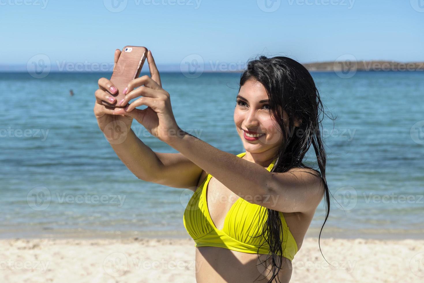 black hair latina girl portrait taking selfie on the sea background photo