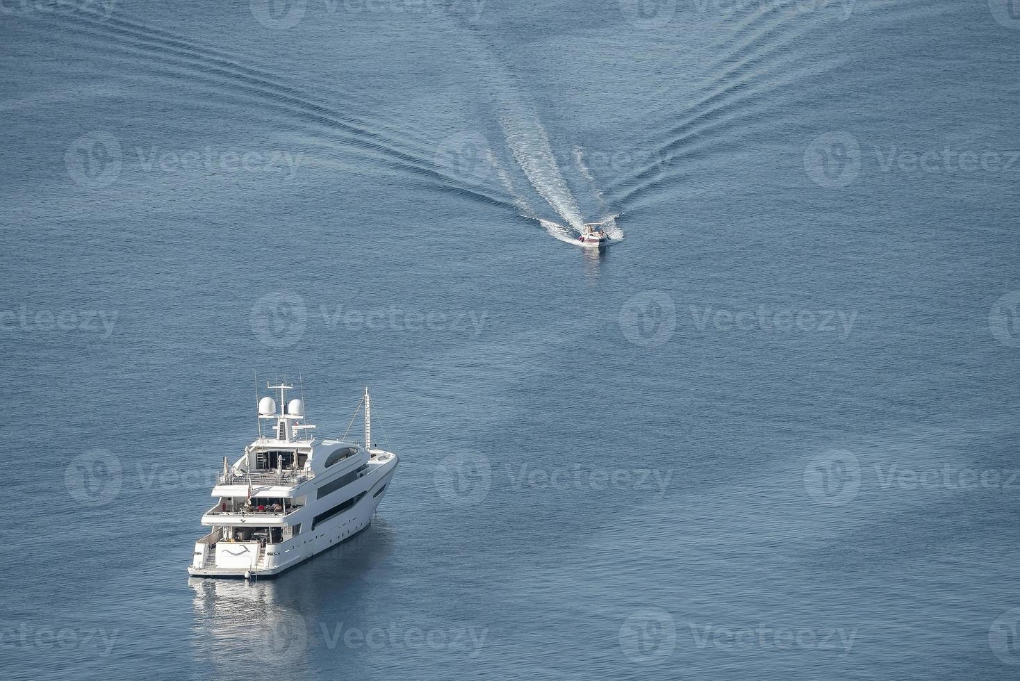 High angle view of motor boat moving by luxurious yacht on beautiful seascape photo