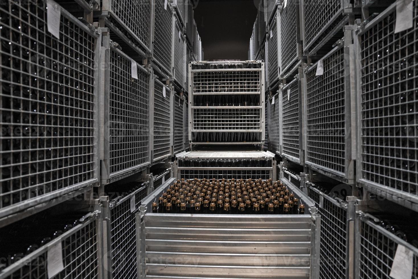 Glass bottles arranged in metallic storage containers at winery photo