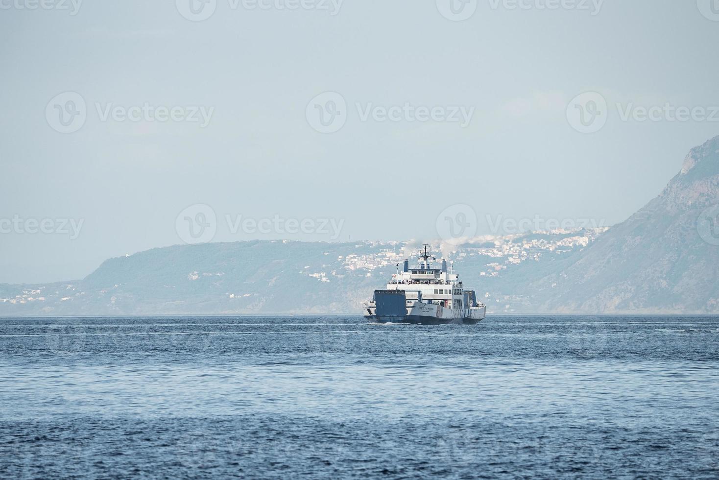 Ship moving on sea against mountain with blue sky in background photo