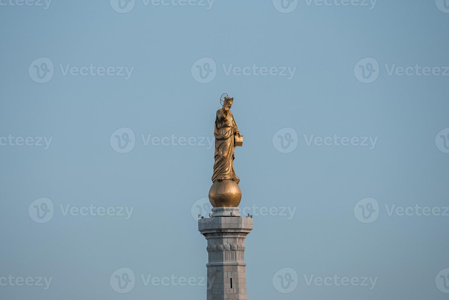 Low angle view of beautiful Statue of Golden Madonna with blue sky in background photo
