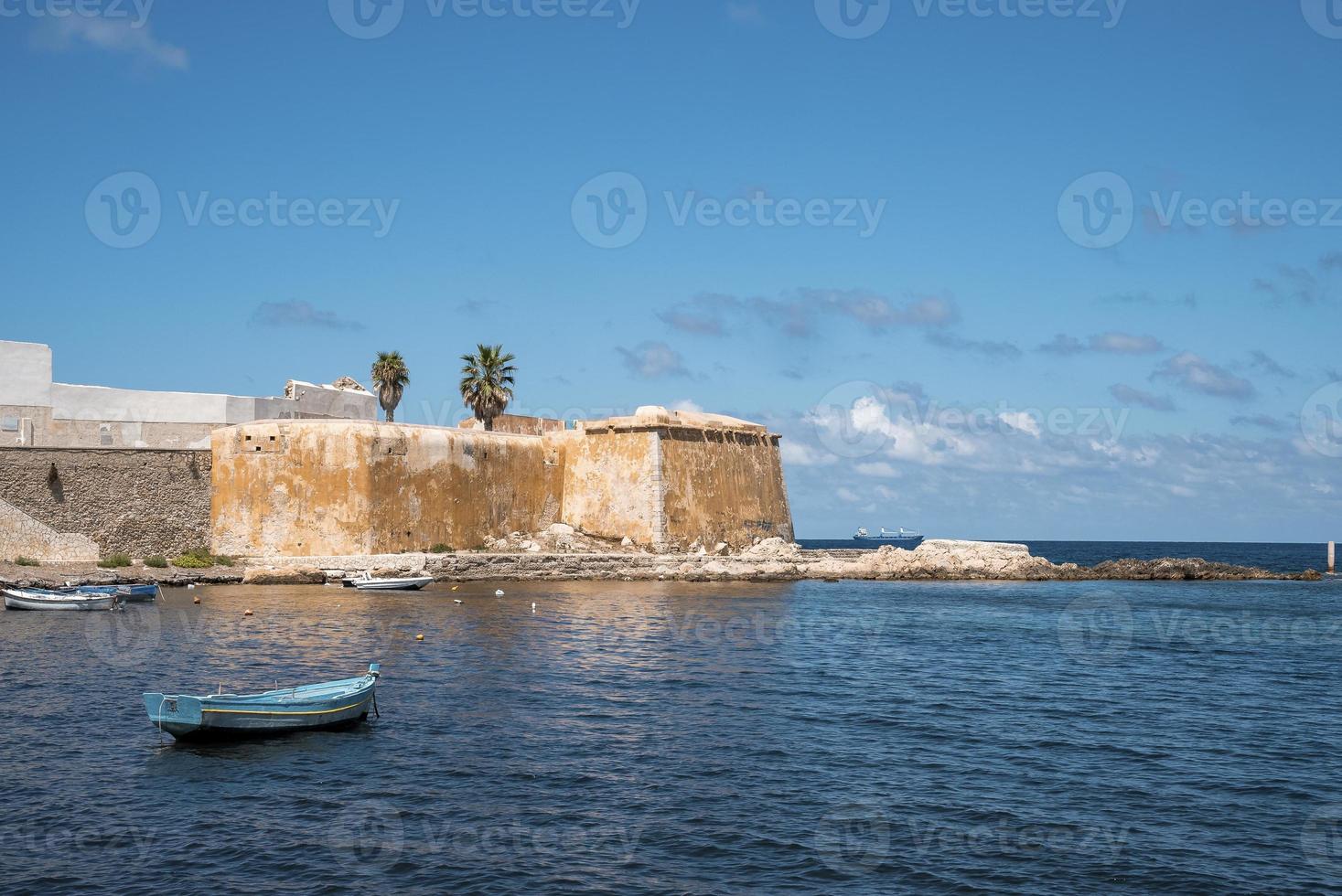Boat moored on sea with Conca Bastion in background on Island during sunny day photo